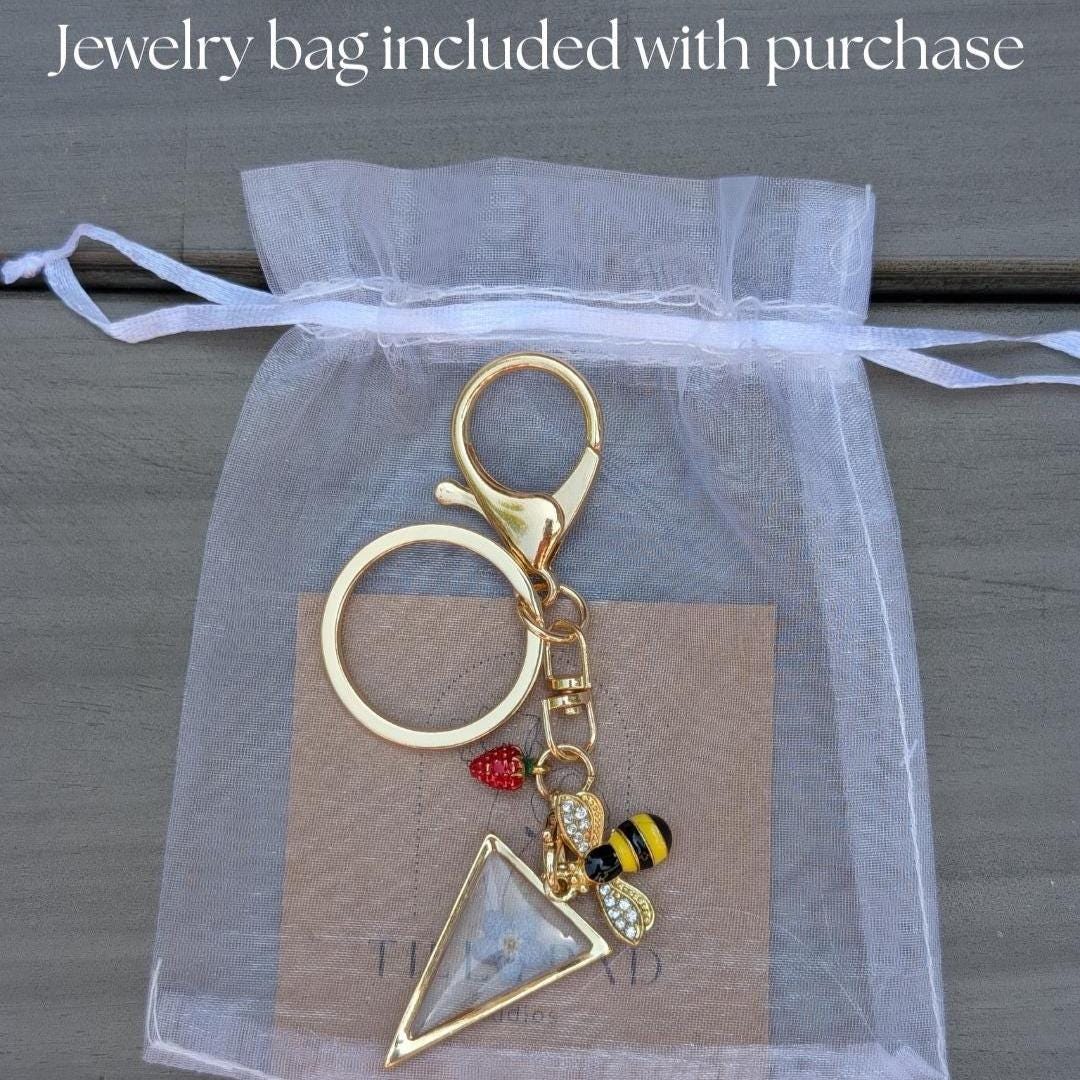 Nature themed keychain with pressed flower triangle charm gold hardware and whimsical bee and berry charms for purse or backpack