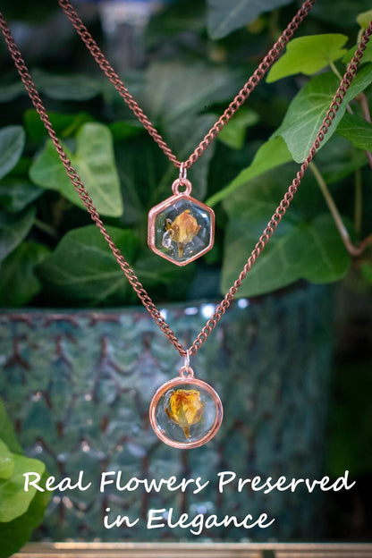 Real rose jewelry photographed on a wood background with soft lighting. This handmade piece features a preserved pink rose in clear resin, hung on an adjustable chain — a nature-inspired treasure made to celebrate love, growth, and beauty.