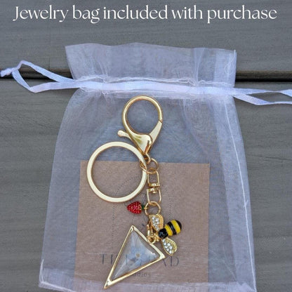 Nature themed keychain with pressed flower triangle charm gold hardware and whimsical bee and berry charms for purse or backpack