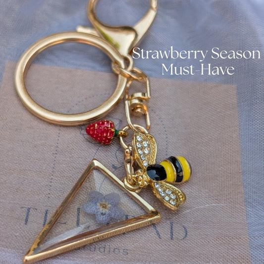 Gold bee charm keychain with triangle pressed flower charm and strawberry accent nature inspired bag charm for cottagecore gift ideas